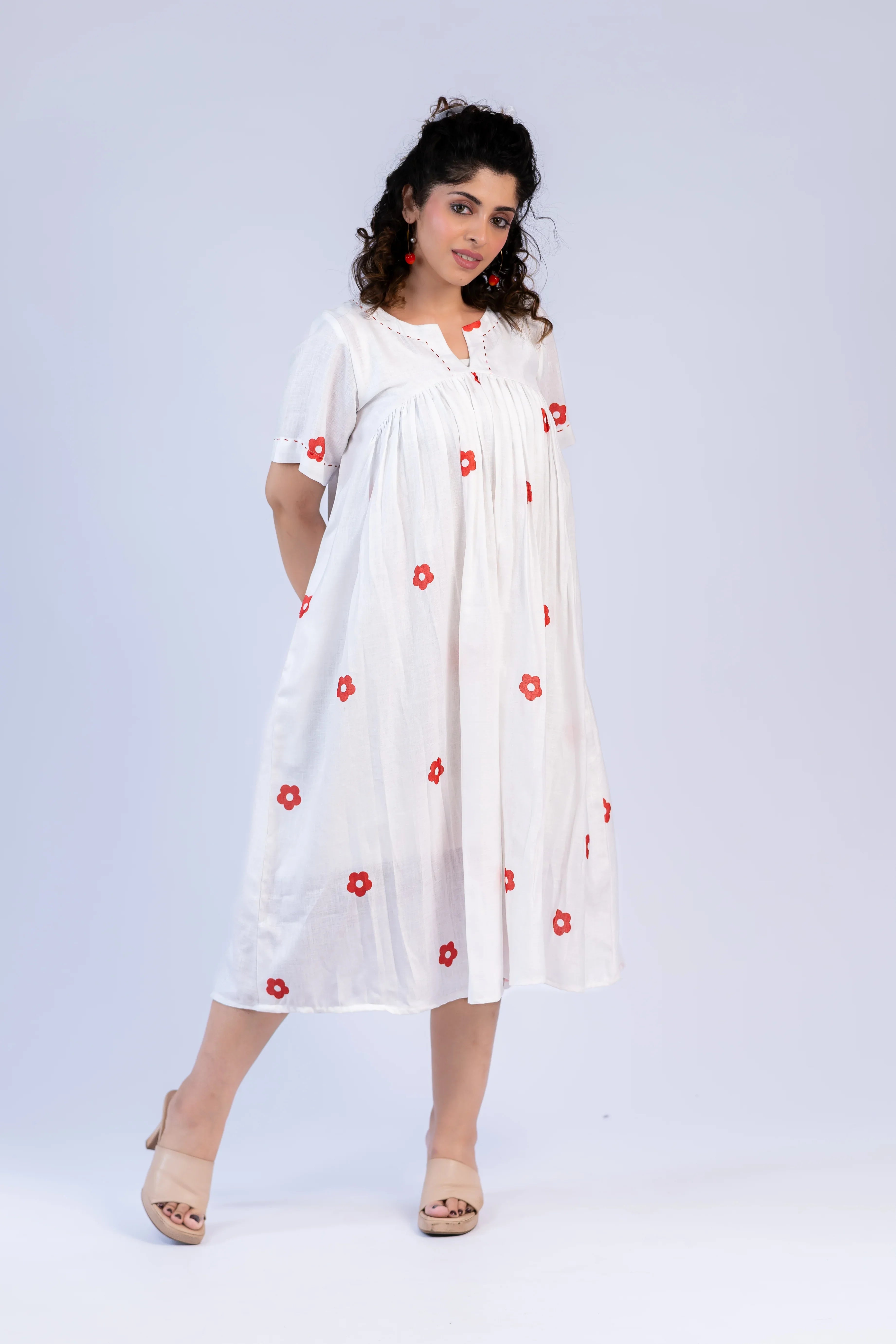 Woman wearing a white dress with red floral patterns on a light gray background