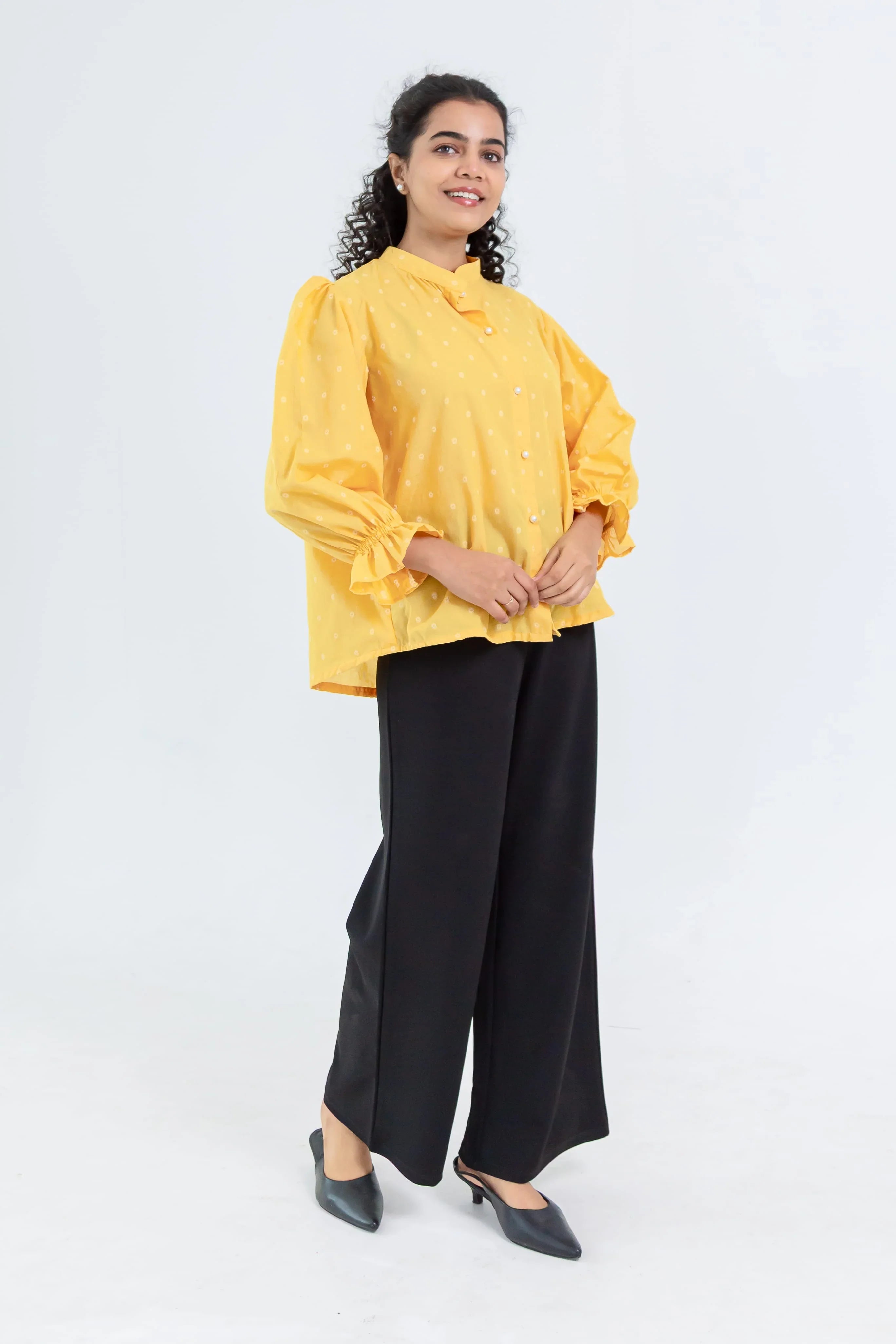 Woman in a yellow polka dot blouse with puff sleeves and black wide-leg pants