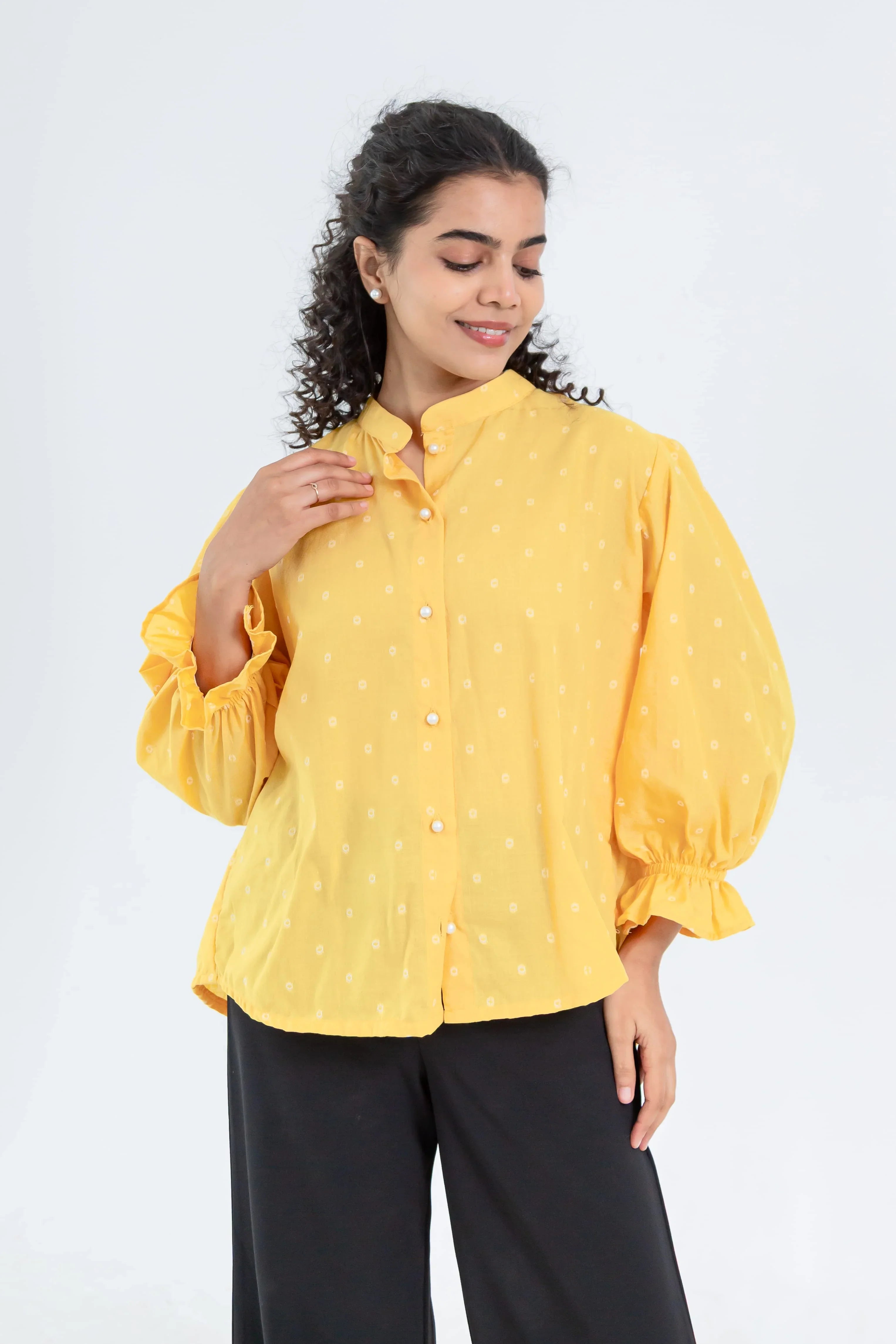 Woman wearing yellow button-up top with puff sleeves and black trousers, casual style