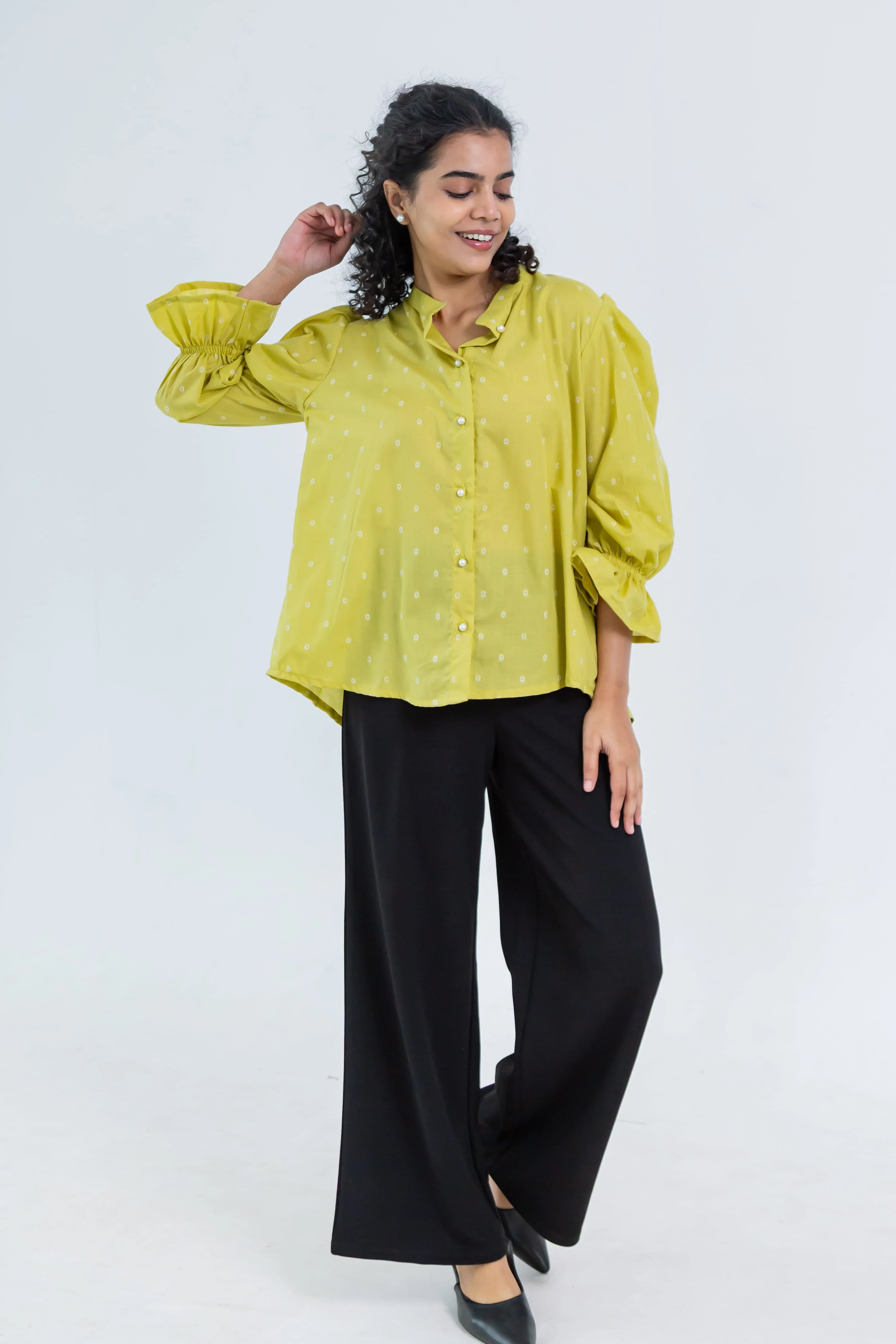 Woman in a yellow polka dot shirt with puff sleeves and black wide leg pants