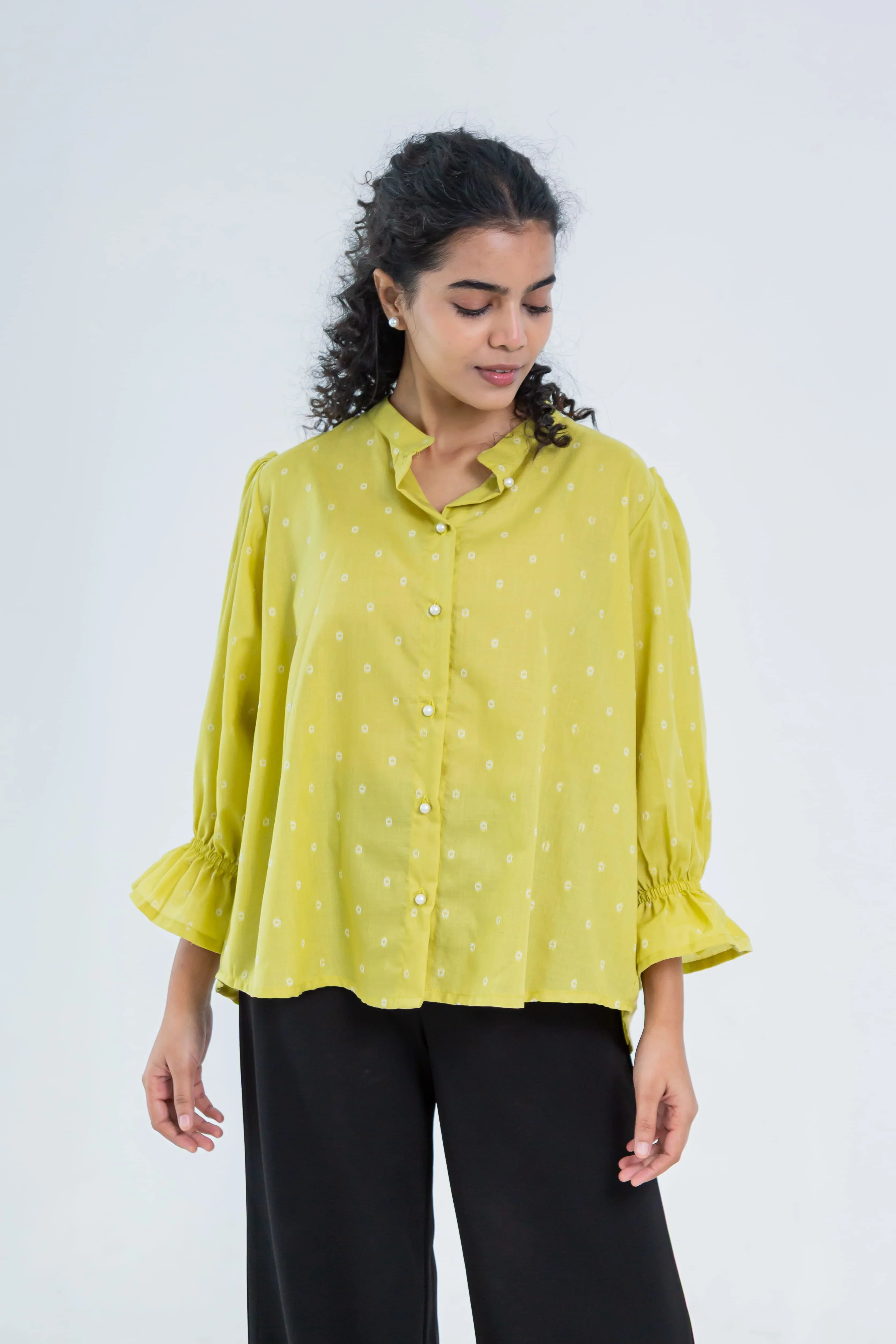 Woman wearing a yellow polka dot button-up top with 3/4 sleeves and black pants