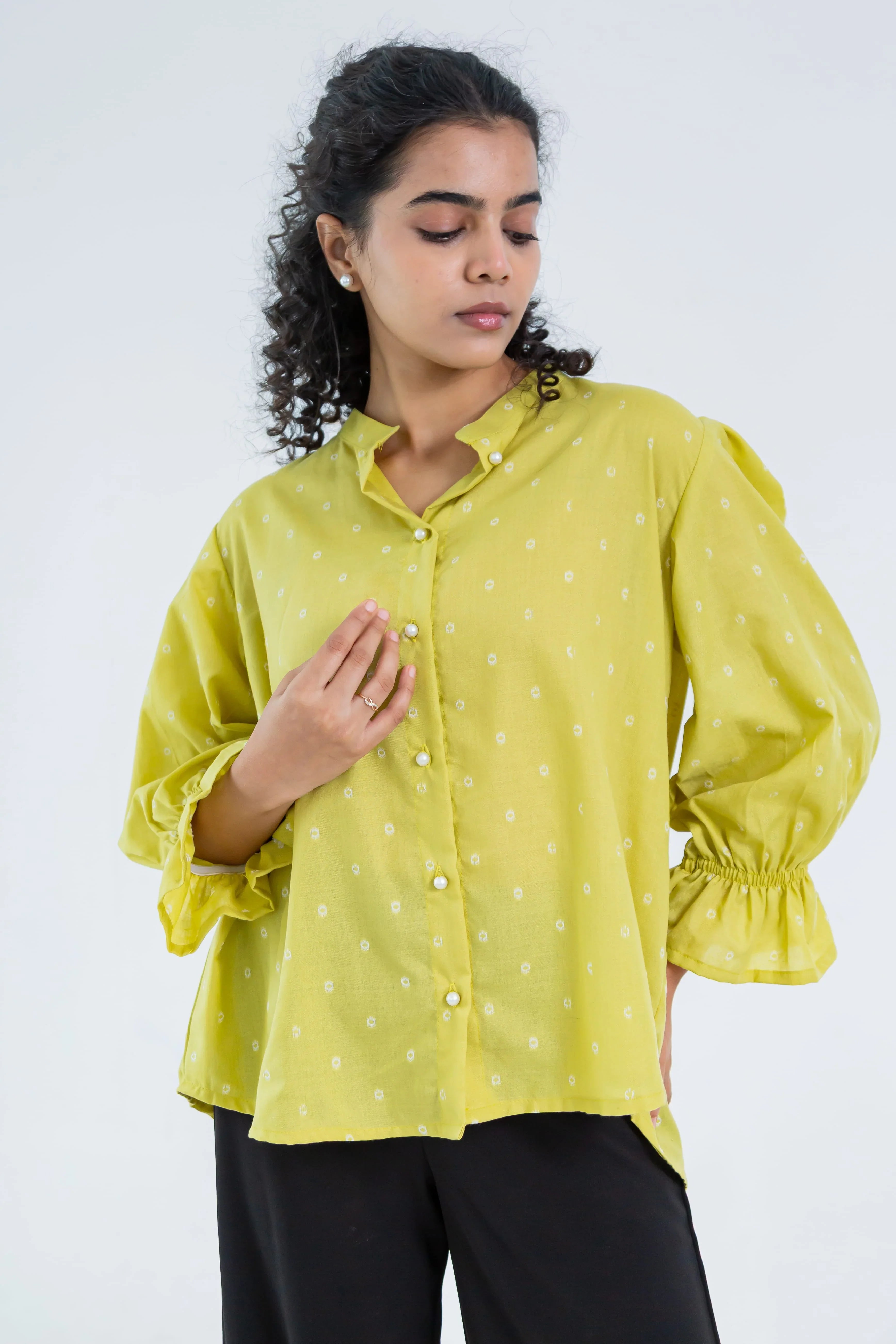 Woman modeling a yellow button-down shirt with puff sleeves and polka dot details