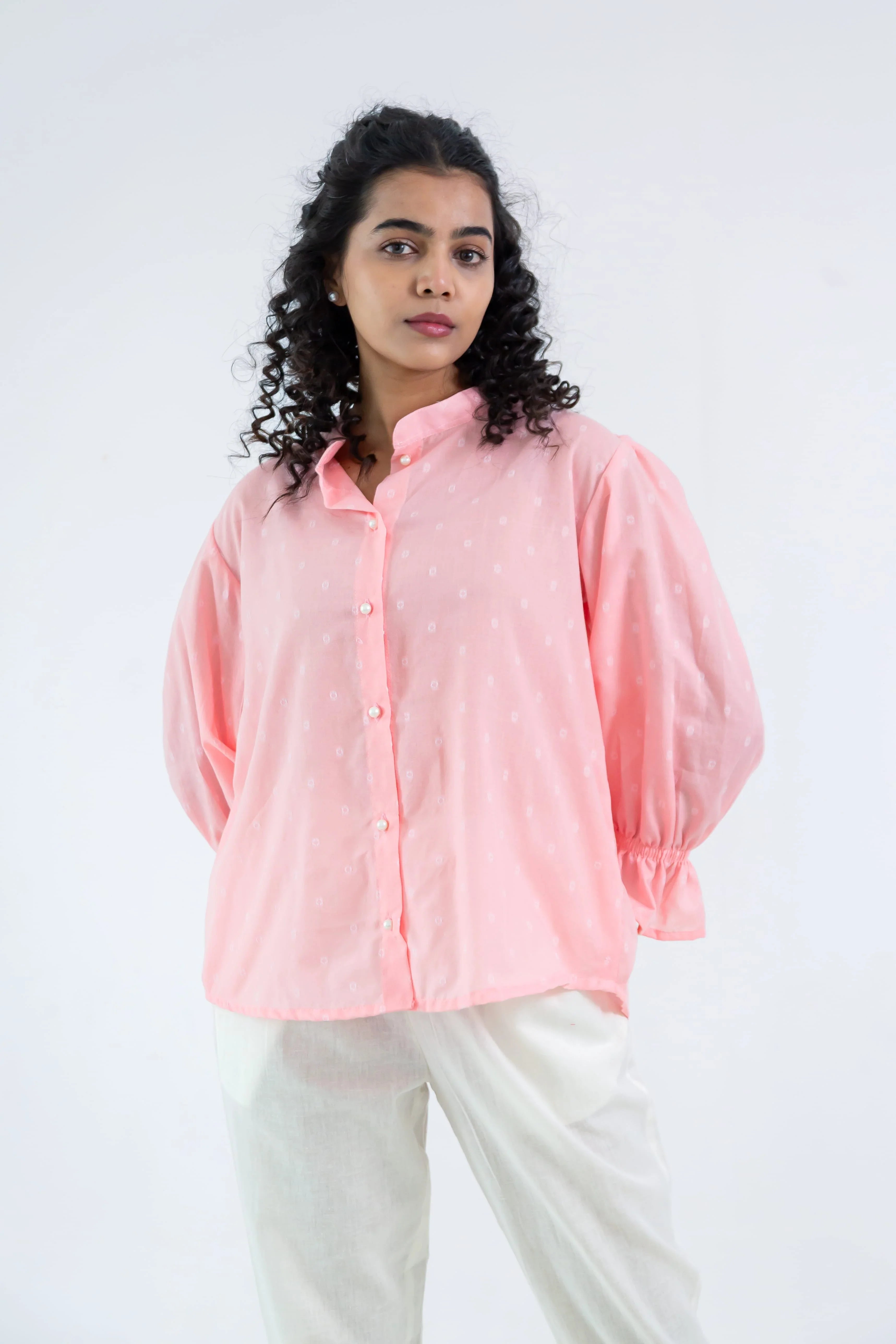 Woman wearing light pink button-up long sleeve shirt and white pants, stylish casual outfit