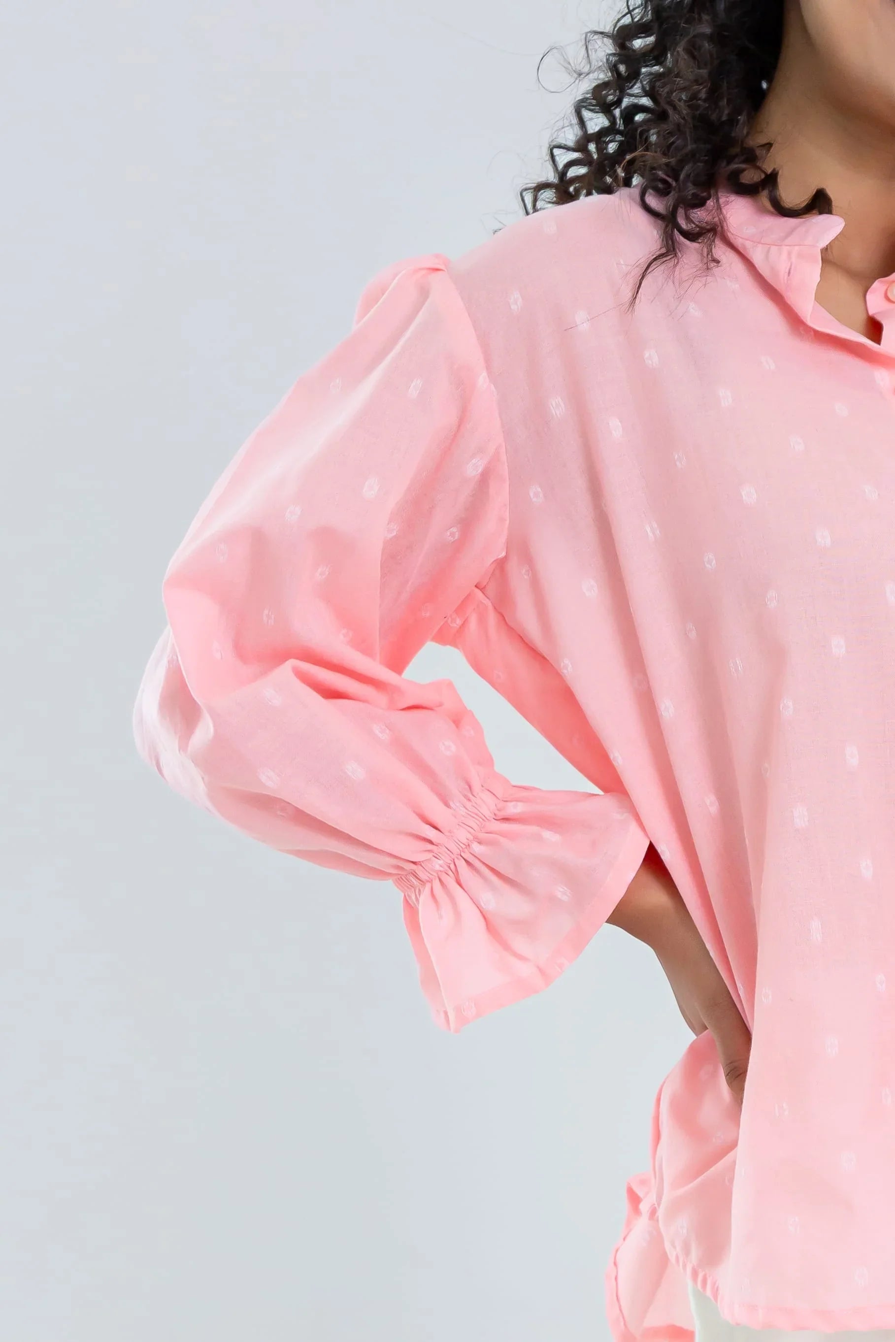 Light pink polka dot blouse with ruffled collar and puffed long sleeves, close-up view