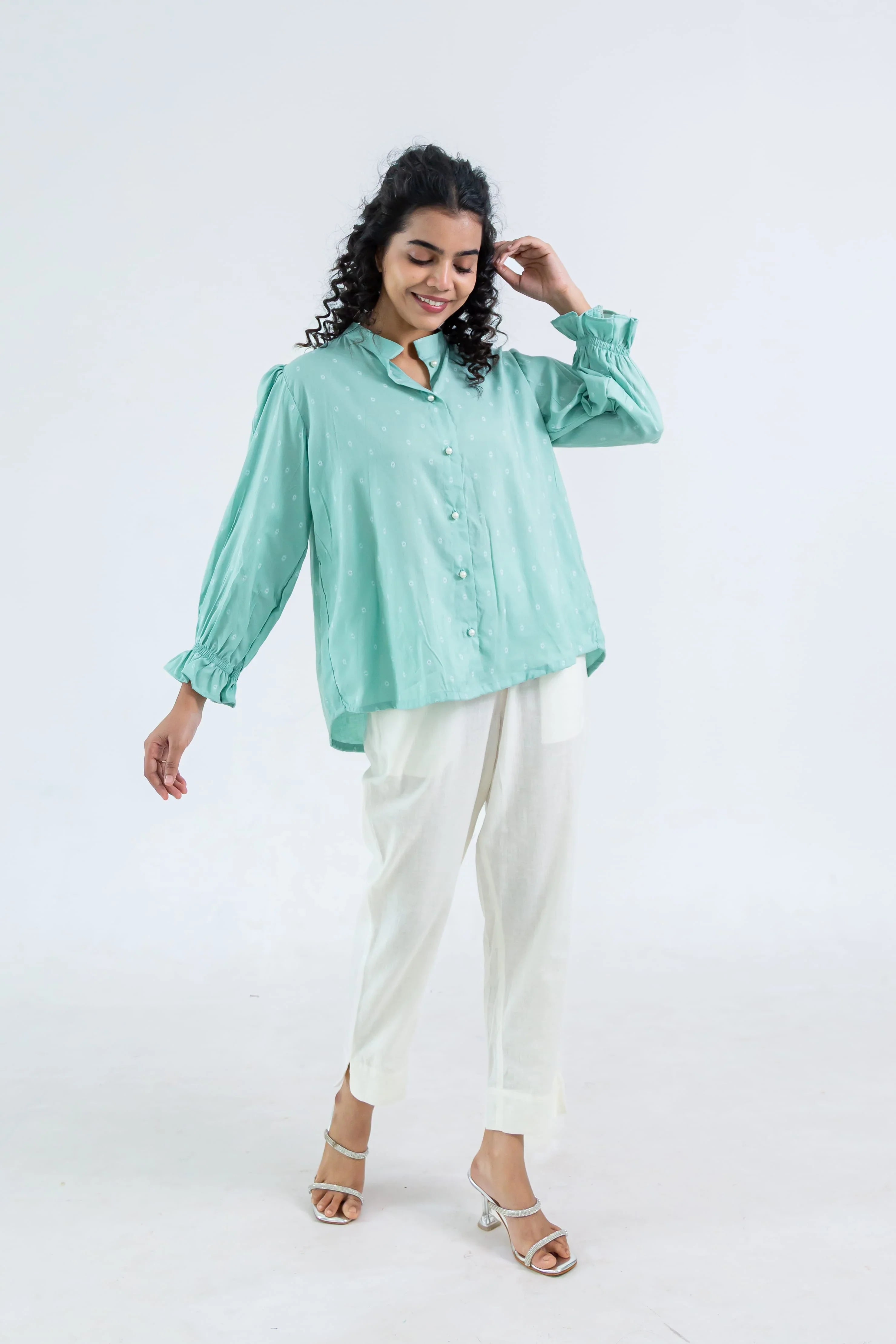 Woman in light green button-up top and white pants, trendy casual outfit