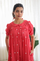 Woman in a red polka dot dress with puff sleeves and Peter Pan collar, indoor setting