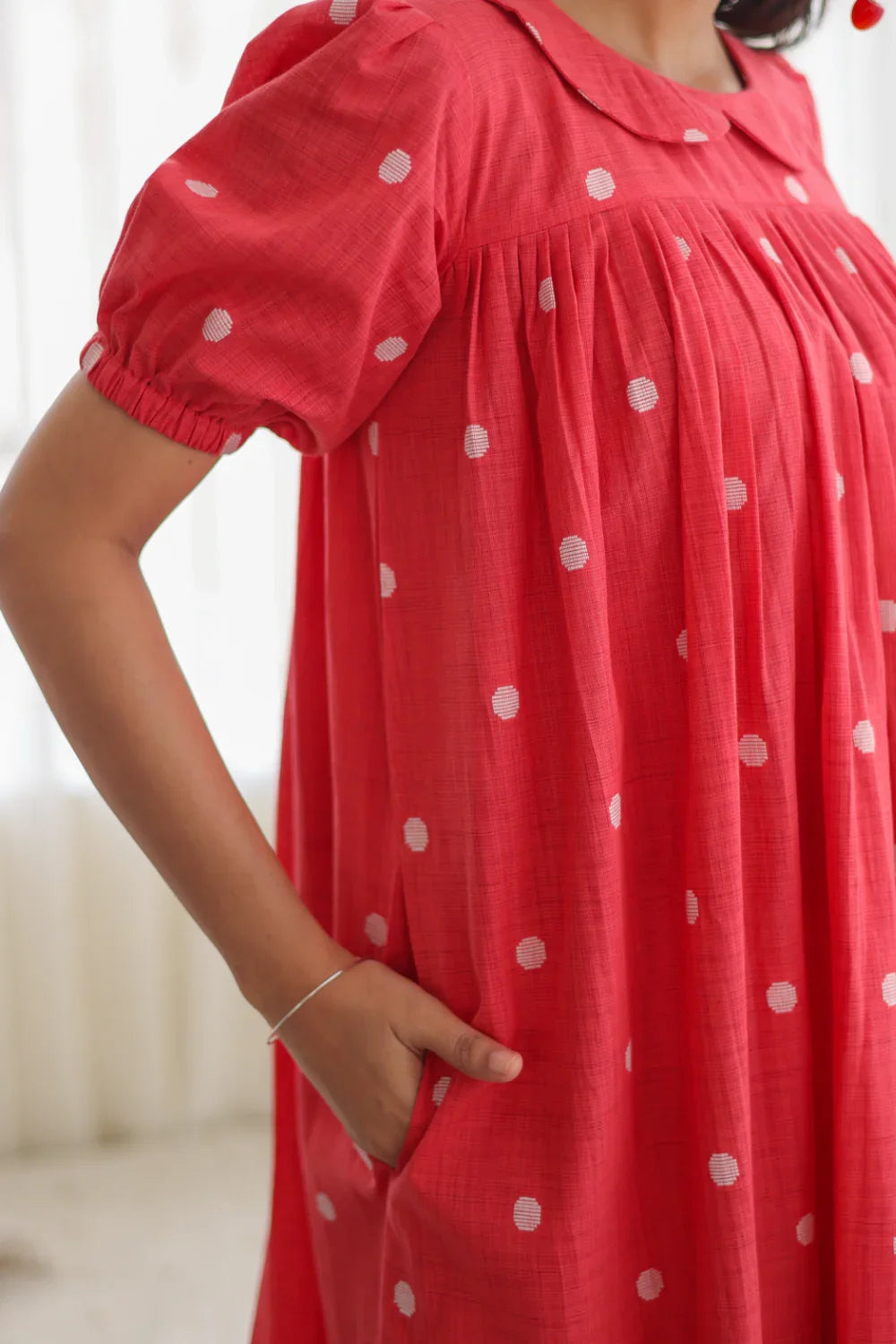 Close-up of woman wearing a red polka dot dress with puff sleeves and side pockets