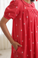 Close-up of woman wearing a red polka dot dress with puff sleeves and side pockets
