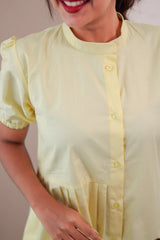 Woman in pastel yellow button-front dress with short puff sleeves and mandarin collar
