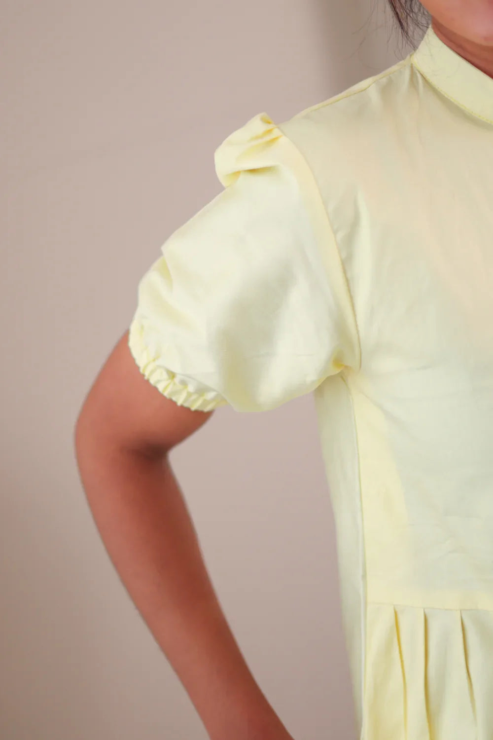 Close-up of a pastel yellow puff sleeve dress with pleated detail