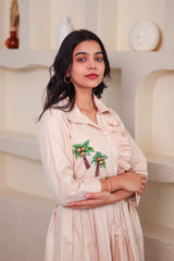 Woman in beige embroidered dress with palm tree motif, stylish everyday outfit