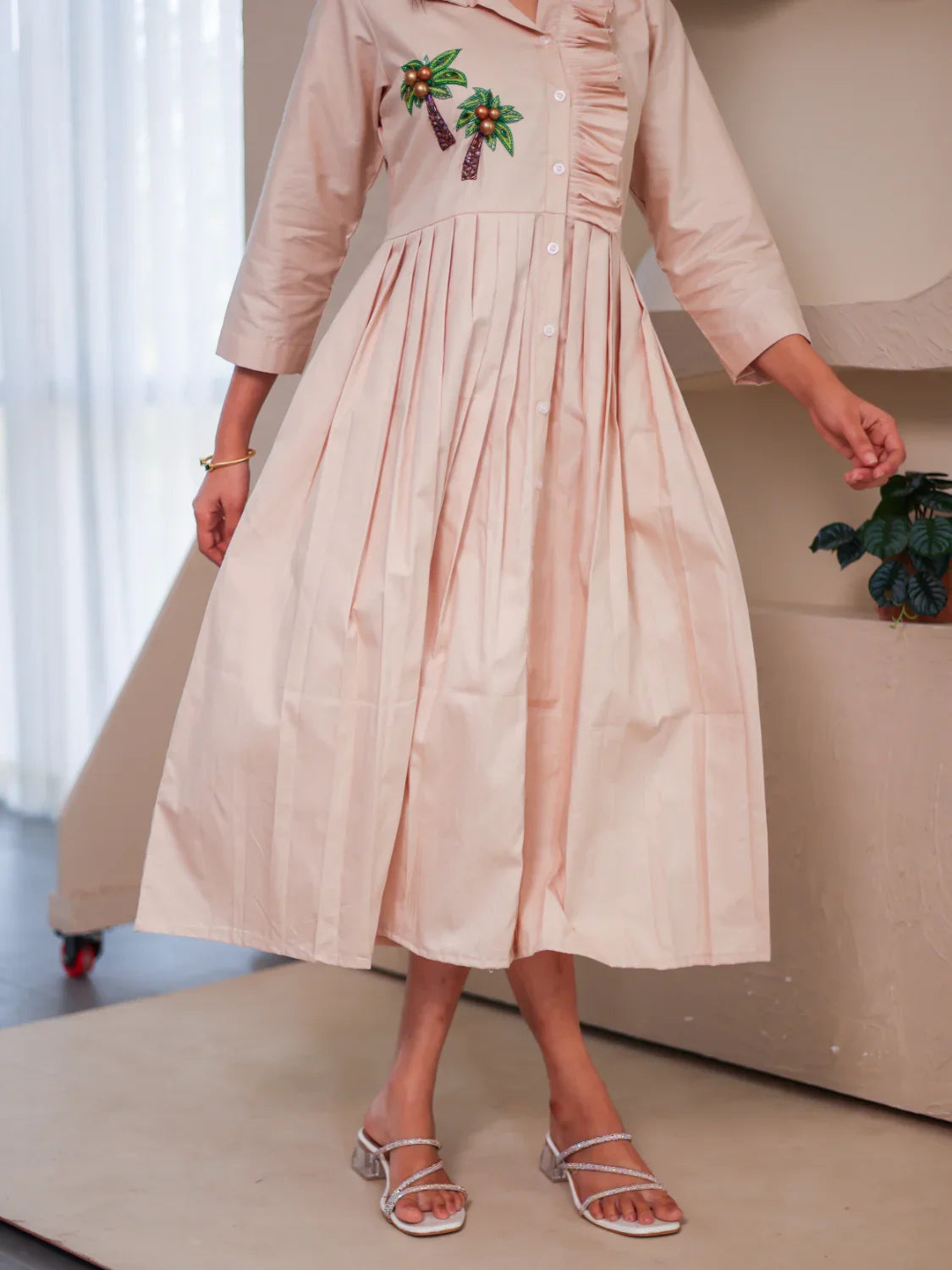 Beige midi dress with palm tree embroidery, three-quarter sleeves, front pleats, and button-down design