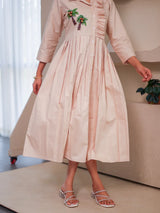 Beige midi dress with palm tree embroidery, three-quarter sleeves, front pleats, and button-down design