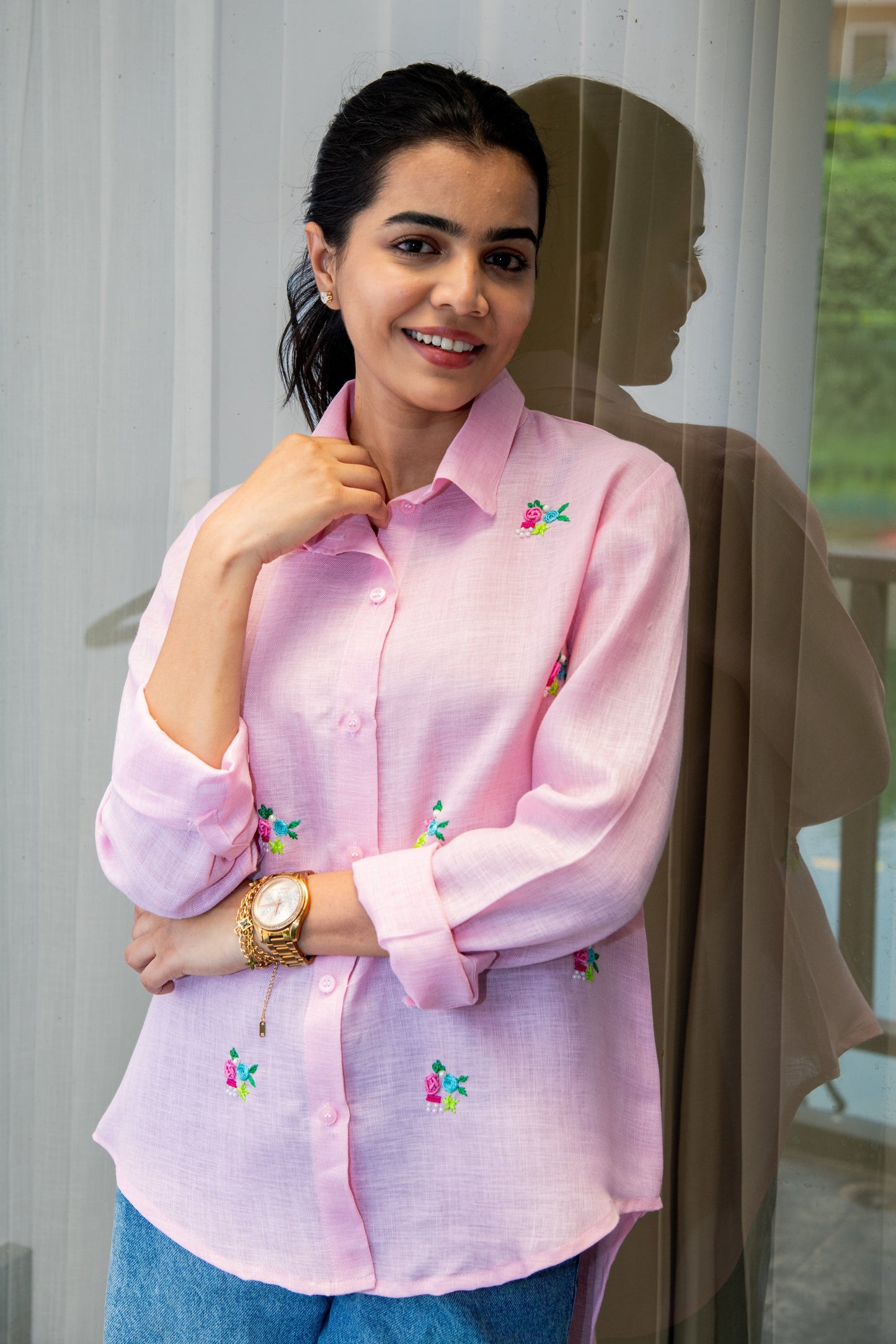 Pink floral embroidered shirt with rolled sleeves, paired with jeans for casual style