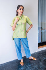 Woman in pastel green embroidered shirt and blue jeans, casual summer outfit