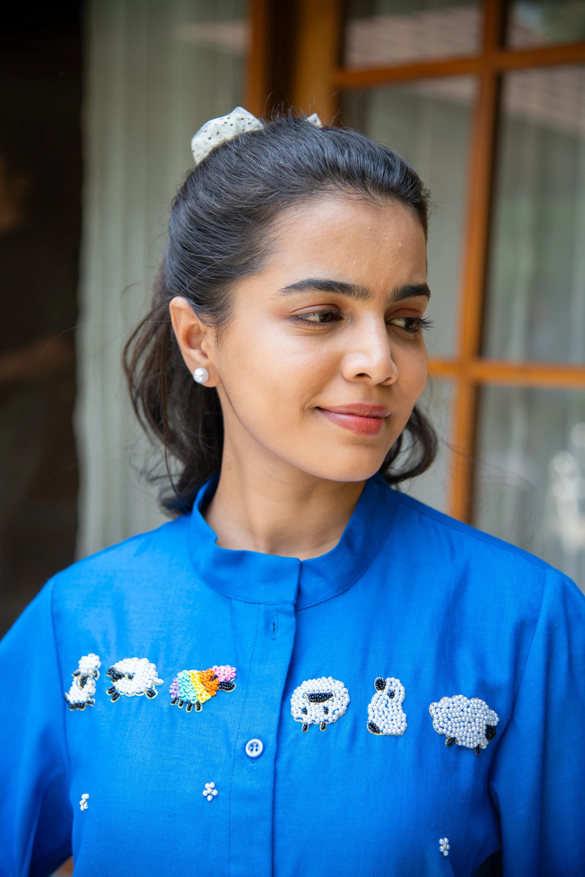 Woman wearing blue shirt with sheep embroidery, casual trendy fashion style