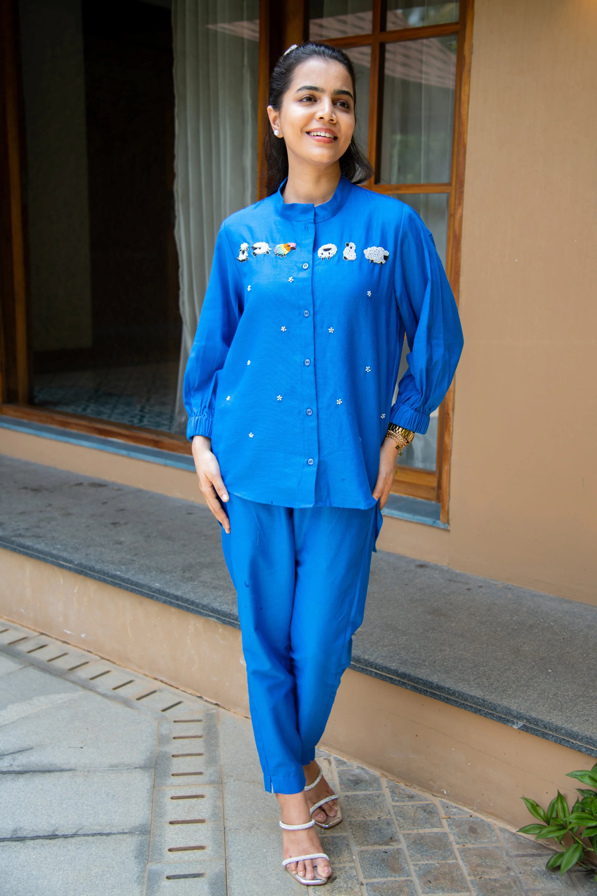 Woman wearing blue embroidered co-ord set with playful motifs, standing outdoors