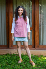 Woman in red and white button-down top with blue denim skirt, standing outdoors on grass