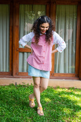 Woman in a pink checkered shirt and denim skirt standing on grass outdoors