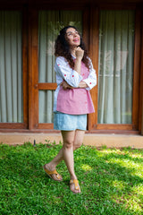 Woman in casual red and white shirt with heart print, denim shorts, and sandals standing on grass