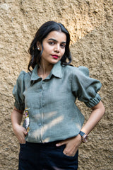 Woman in puff sleeve green linen shirt with bead embroidery, standing outdoors