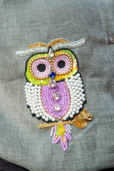 Colorful beaded owl embroidery patch on grey fabric, detailed with sequins and pearls