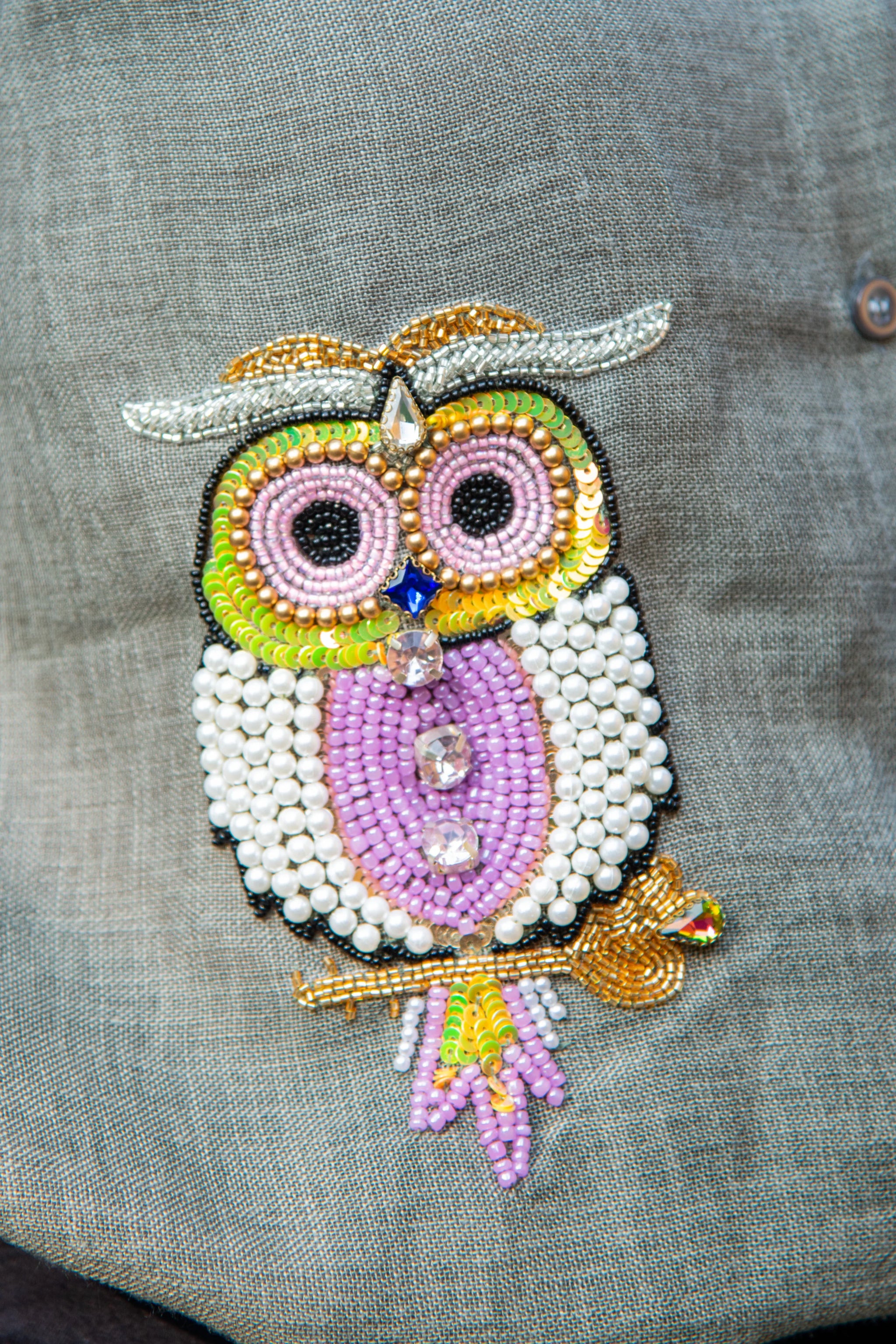 Colorful beaded owl embroidery patch on grey fabric, detailed with sequins and pearls