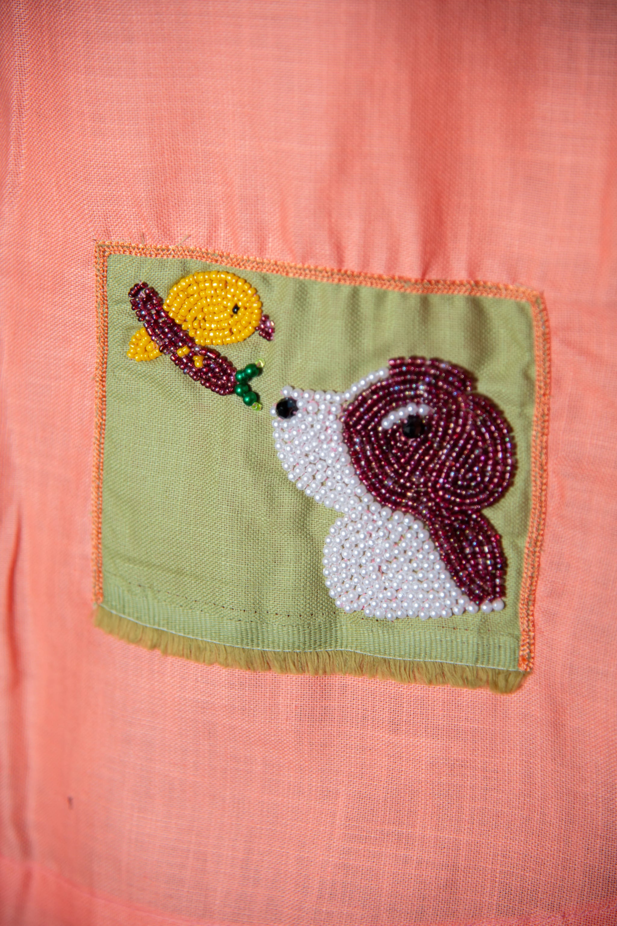 Pink fabric with green pocket, beaded dog and bird embroidery detail