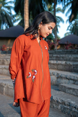Woman wearing an orange embroidered co-ord set with floral details outdoors