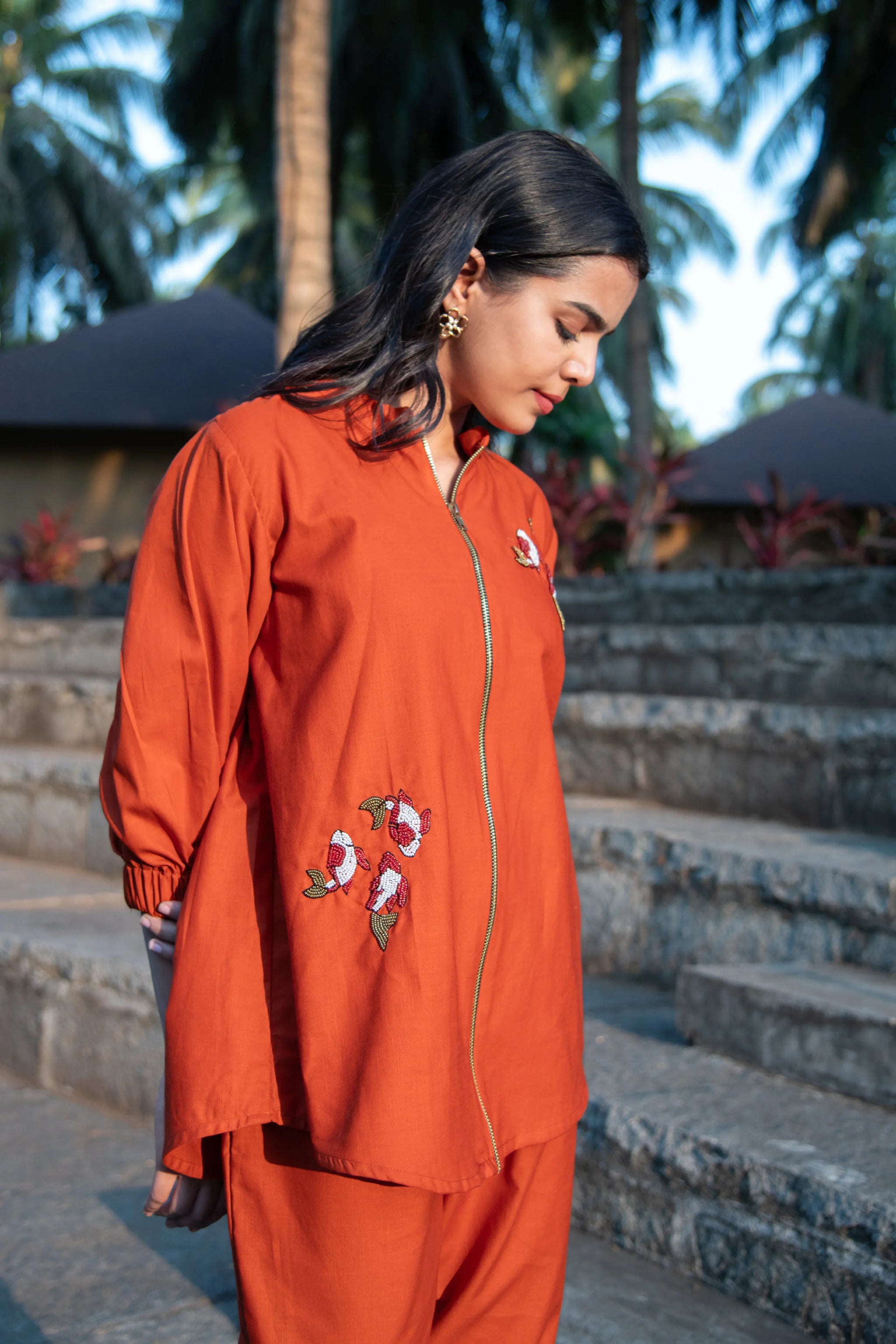 Woman wearing an orange embroidered co-ord set with floral details outdoors
