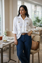 Woman in white embroidered shirt and blue jeans at a cafe