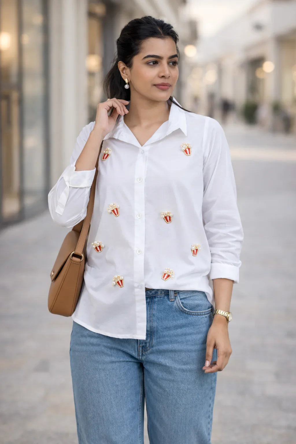 White button-down shirt with popcorn embroidery, paired with blue jeans and a tan bag for casual everyday style.