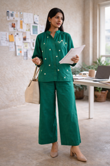 Woman in green floral embroidered co-ord set with wide-leg pants, holding papers in office setting