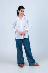 White shirt with popcorn embroidery paired with wide-leg jeans and brown sandals