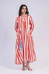 Woman wearing a red and white striped maxi dress with blue fish embroidery, standing indoors.