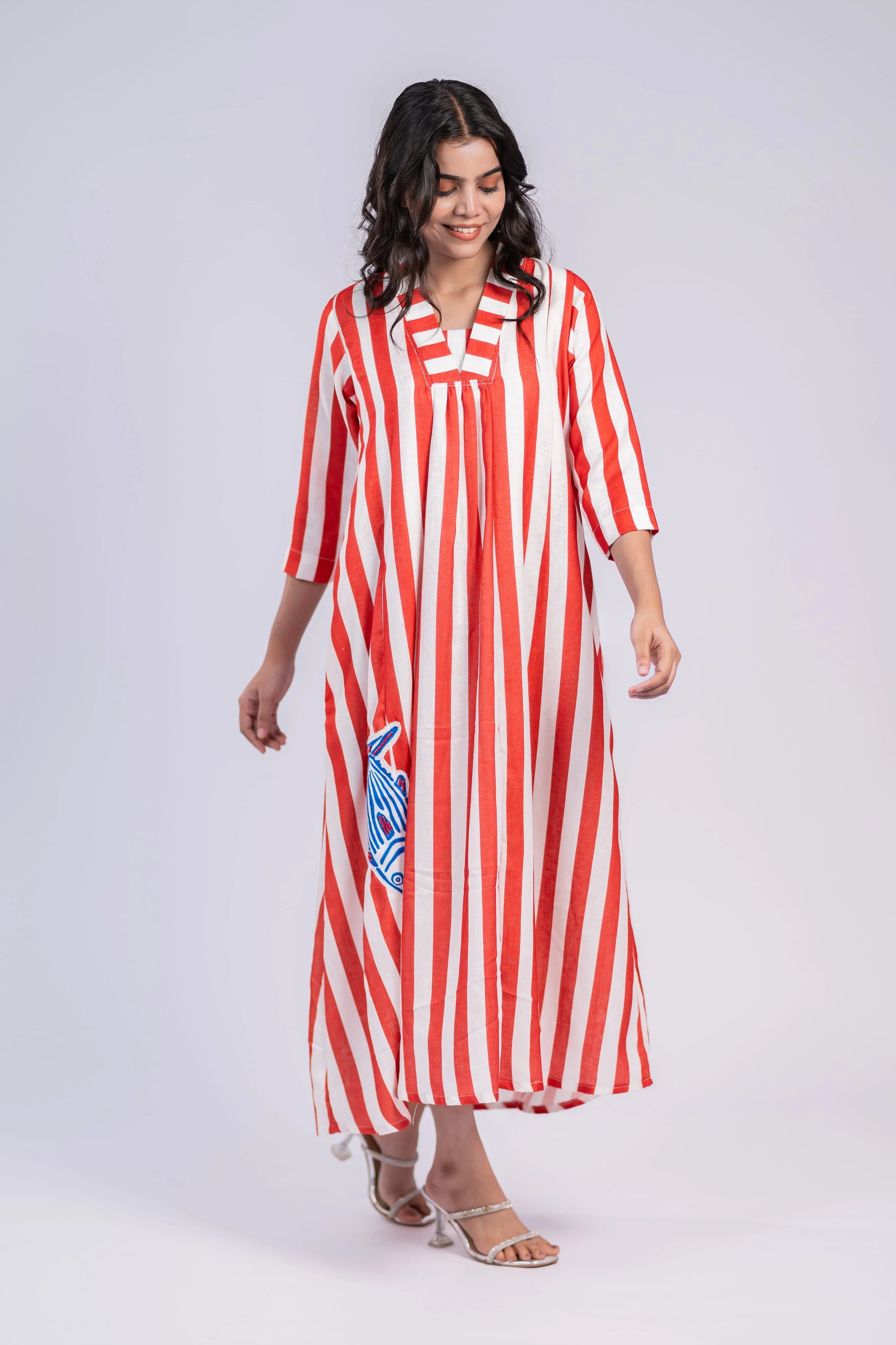 Woman in red and white striped maxi dress with three-quarter sleeves and blue fish patch