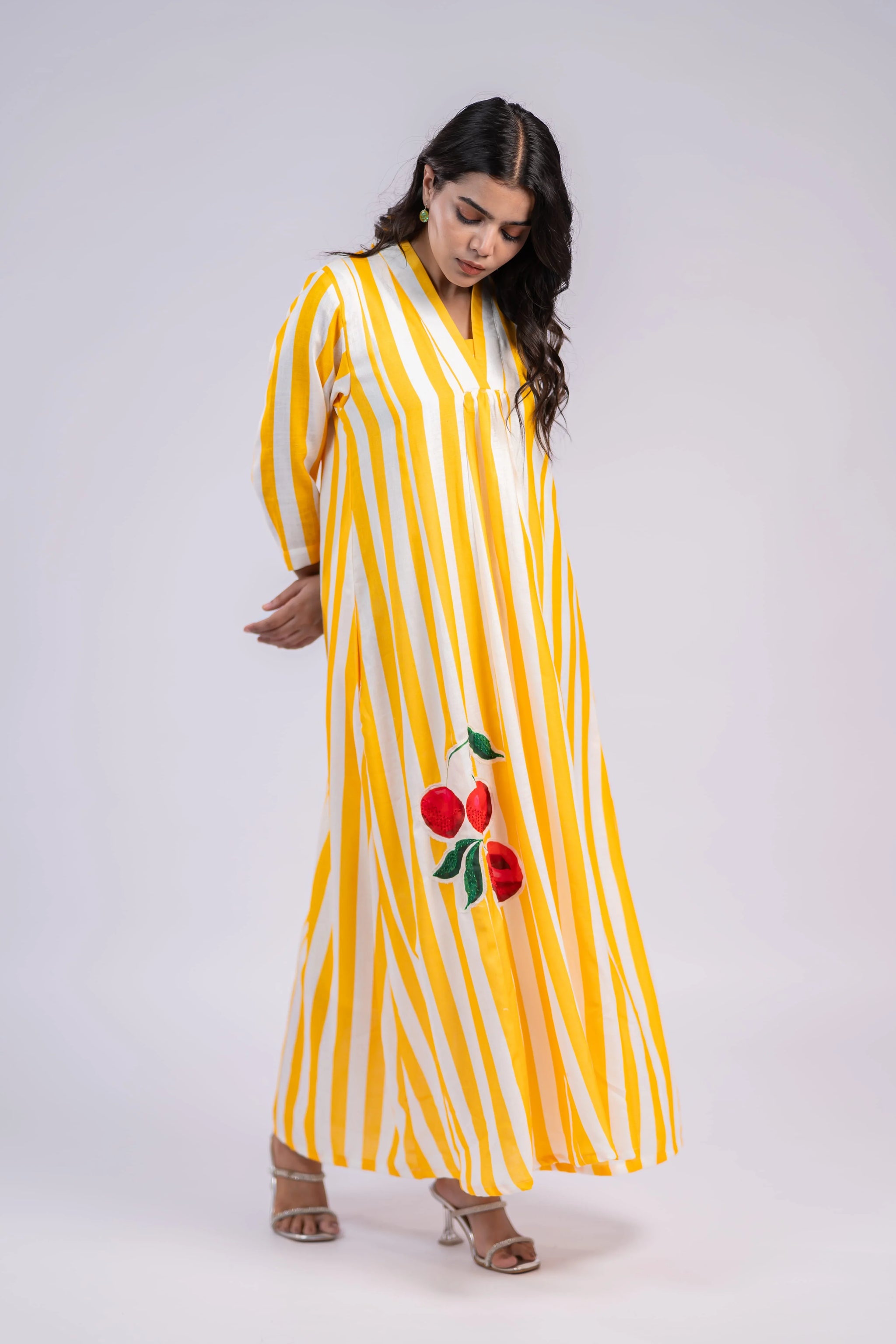 Woman wearing a yellow and white striped maxi dress with red floral embroidery and three-quarter sleeves