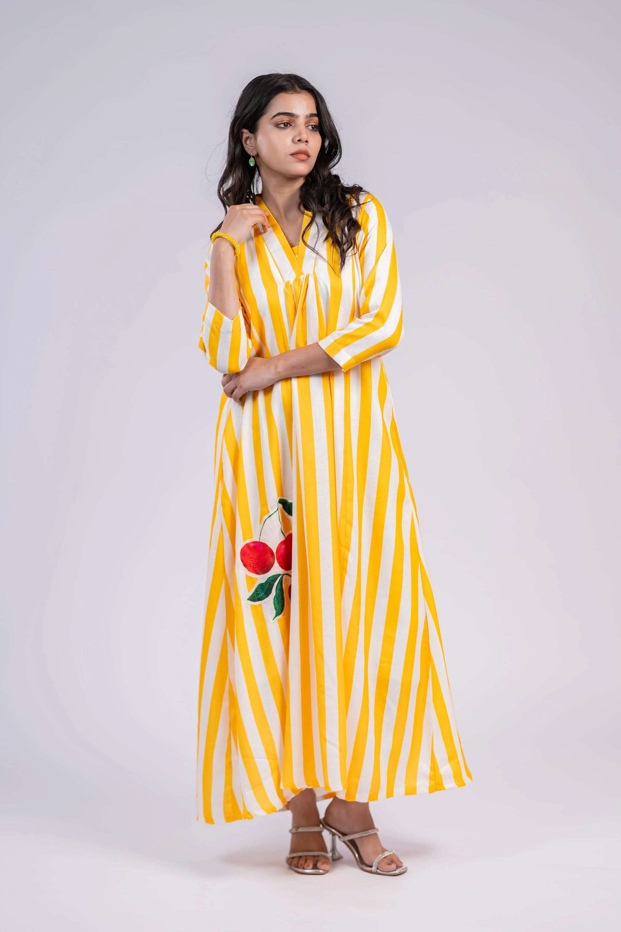 Woman wearing a yellow and white striped maxi dress with cherry print and three-quarter sleeves