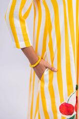 Woman wearing yellow and white striped dress with side pocket, cherry embroidery, yellow bracelet