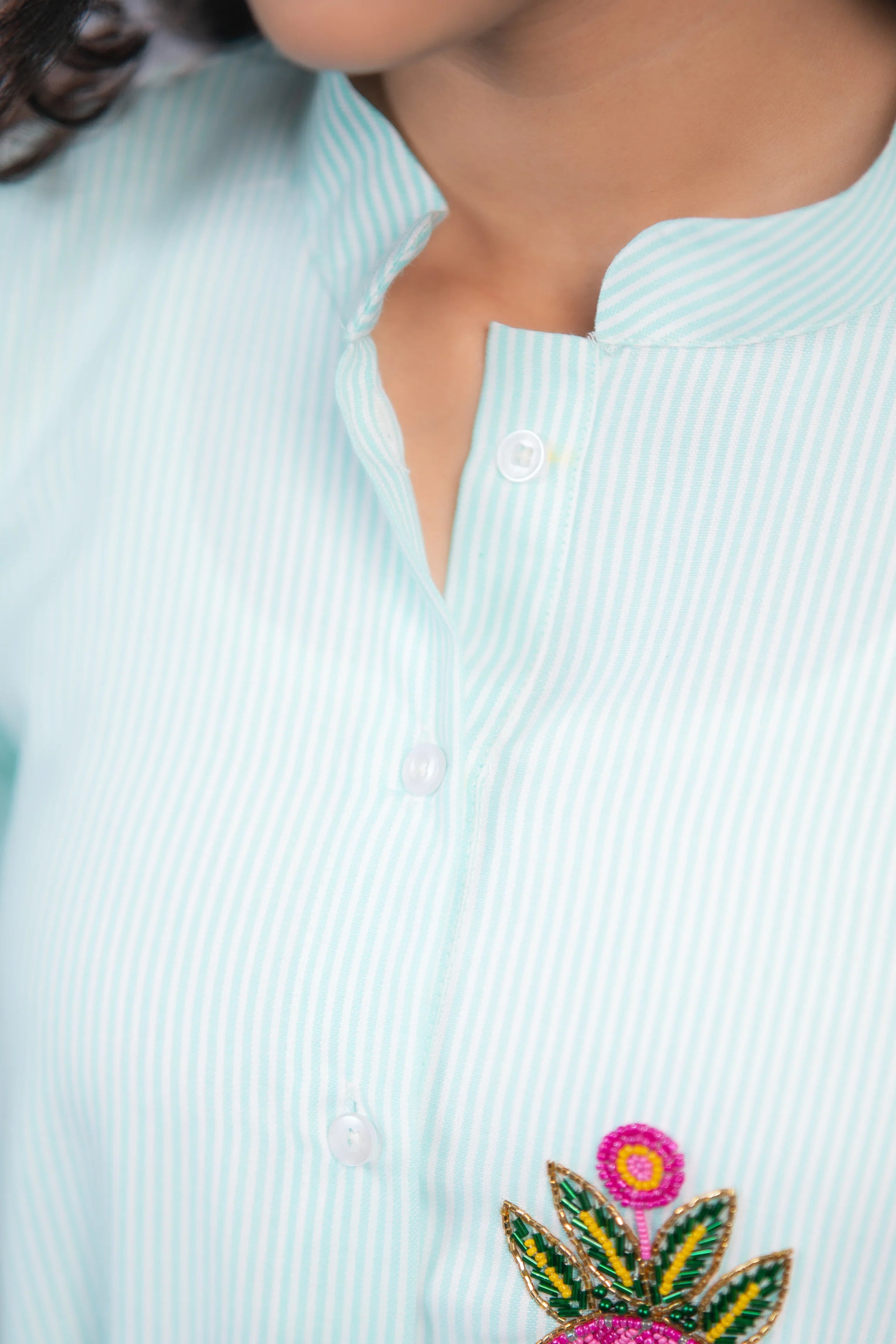 Light blue striped shirt with colorful floral embroidery and button details
