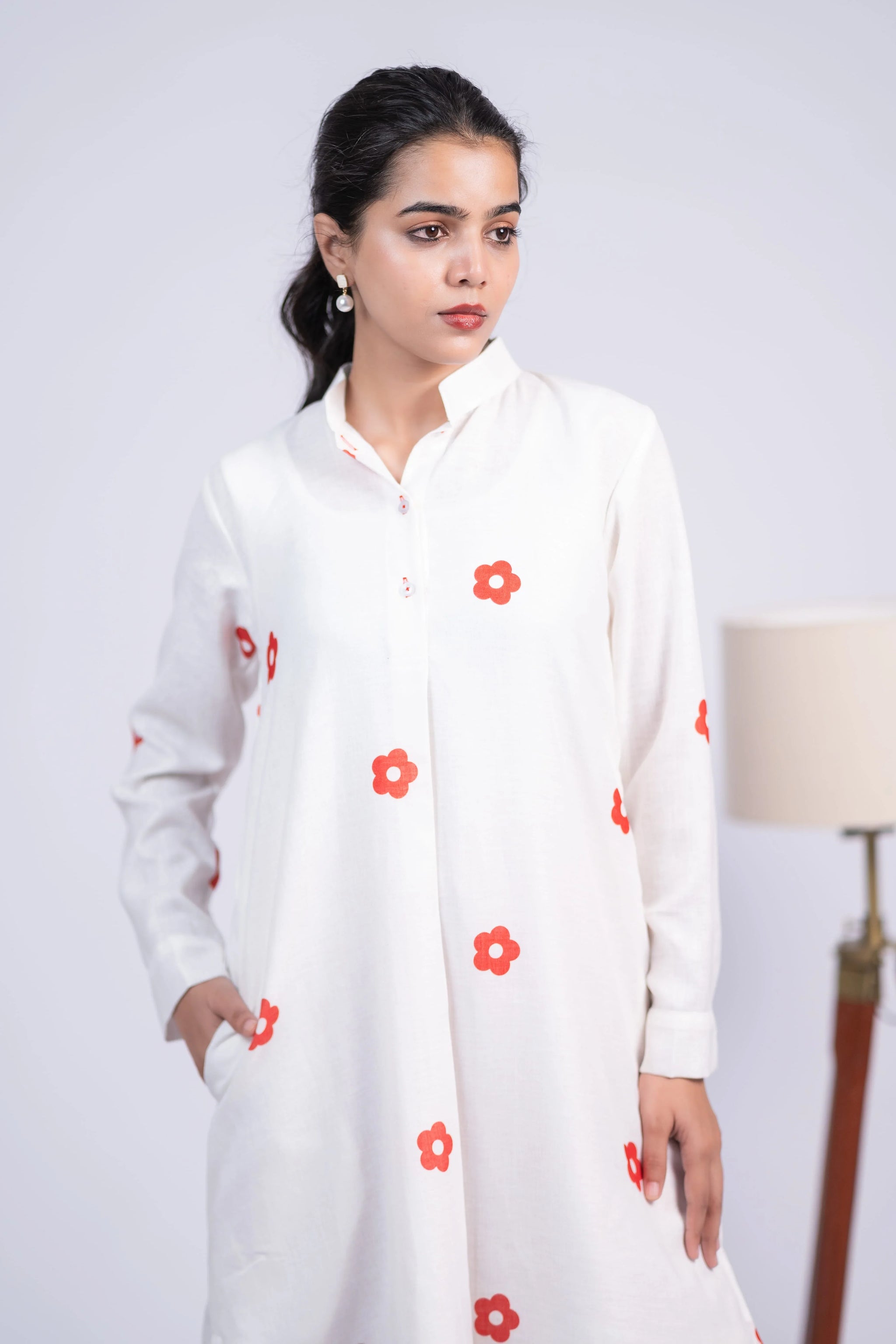 Woman in white kurta with red floral prints, long sleeves, and mandarin collar