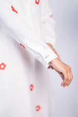 White women's dress with red floral print and long sleeves, close-up of cuff detail