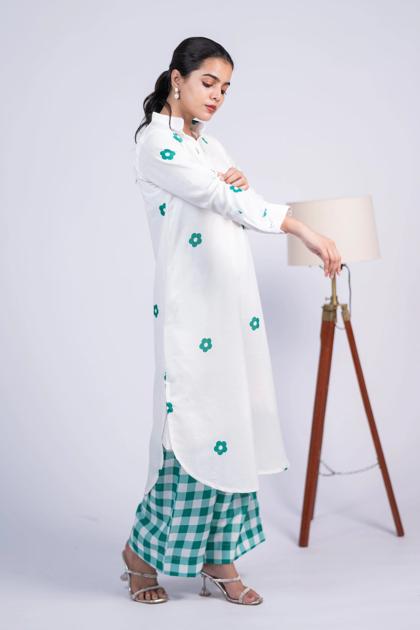 Woman in a white floral kurta and green checkered pants, standing indoors