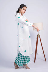 Woman in a white floral kurta and green checkered pants, standing indoors