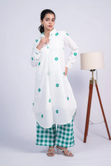 Woman in a white floral kurta with green checkered pants, standing indoors