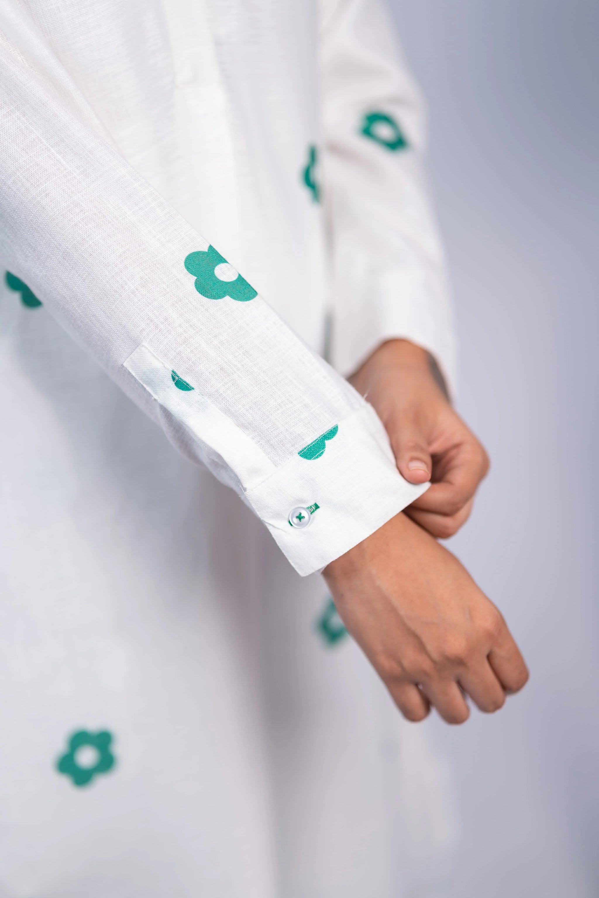 Close-up of a white women’s dress with green floral print and button cuff detail