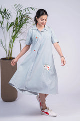 Woman wearing a striped midi dress with playing card motifs and casual sneakers, indoor setting