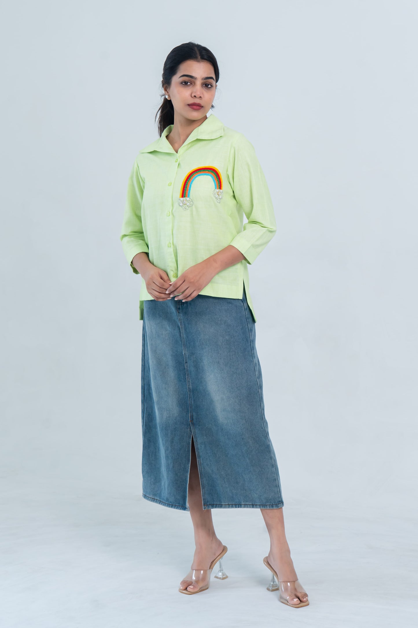 Lime green shirt with rainbow embroidery paired with denim midi skirt and clear heels