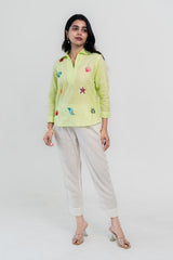 Lime green embroidered shirt with starfish and shells, paired with white pants and clear heels