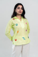 Lime green embroidered shirt with colorful sea motifs, paired with white pants for casual wear